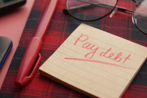 Pay debt written on a page with pen and glasses