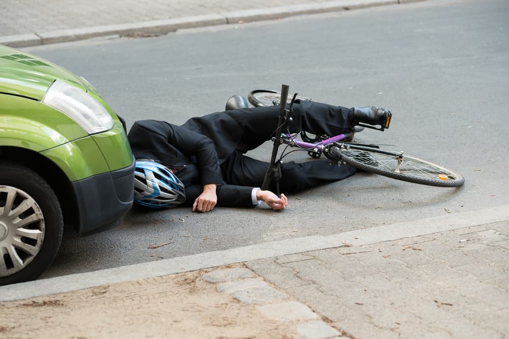 An unconscious male cyclist lies on the road following a severe accident, emphasizing the need for enhanced road safety and driver awareness.