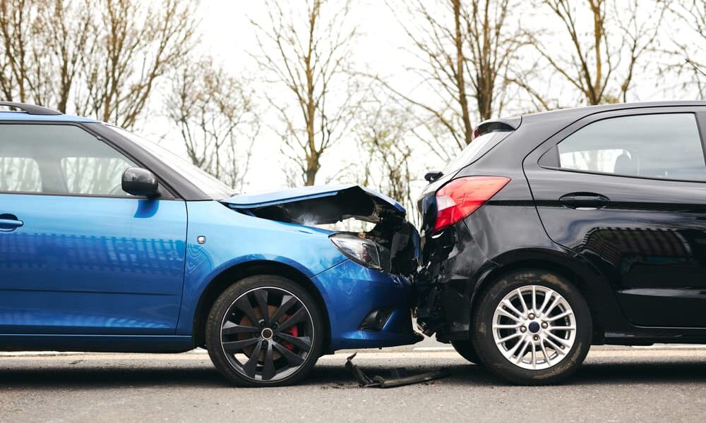 Two damaged cars pulled over to the side of the road after a traffic accident.