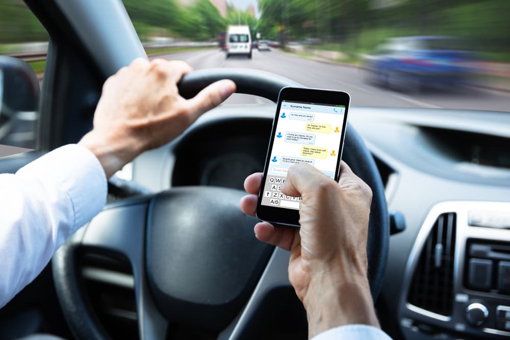 texting - The Ye Law Firm Injury Lawyers Distracted driver using a phone while driving. Woman texting on her mobile device in traffic, highlighting unsafe behavior and the risk of auto accidents.