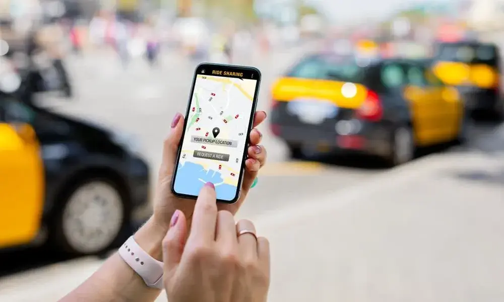 rideshare 2 - The Ye Law Firm Injury Lawyers Passenger woman using a phone in the back seat of a taxi. Rideshare app for commuting or work travel. Professional lady seated, driver visible upfront.