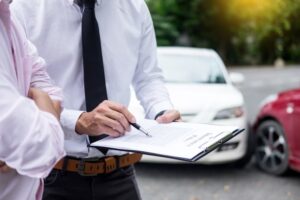 Insurance agent inspecting a vehicle and taking notes on a clipboard while assessing and processing a car accident claim.