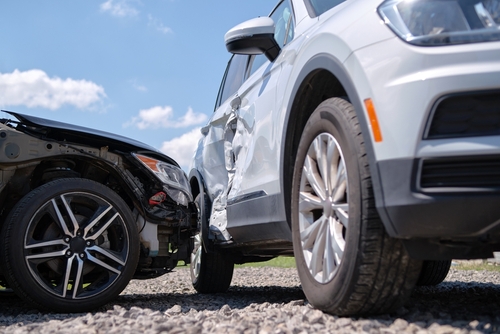 Close-up of two cars involved in a T-bone accident, showing visible damage to the side of a white SUV and the front of a black sedan.