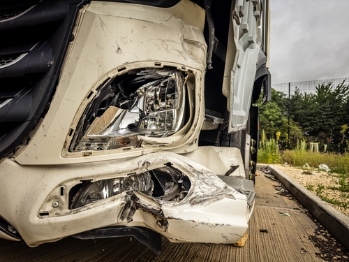 Close-up of a damaged truck front, showing a crumpled bumper and broken headlights, indicating the aftermath of a collision.