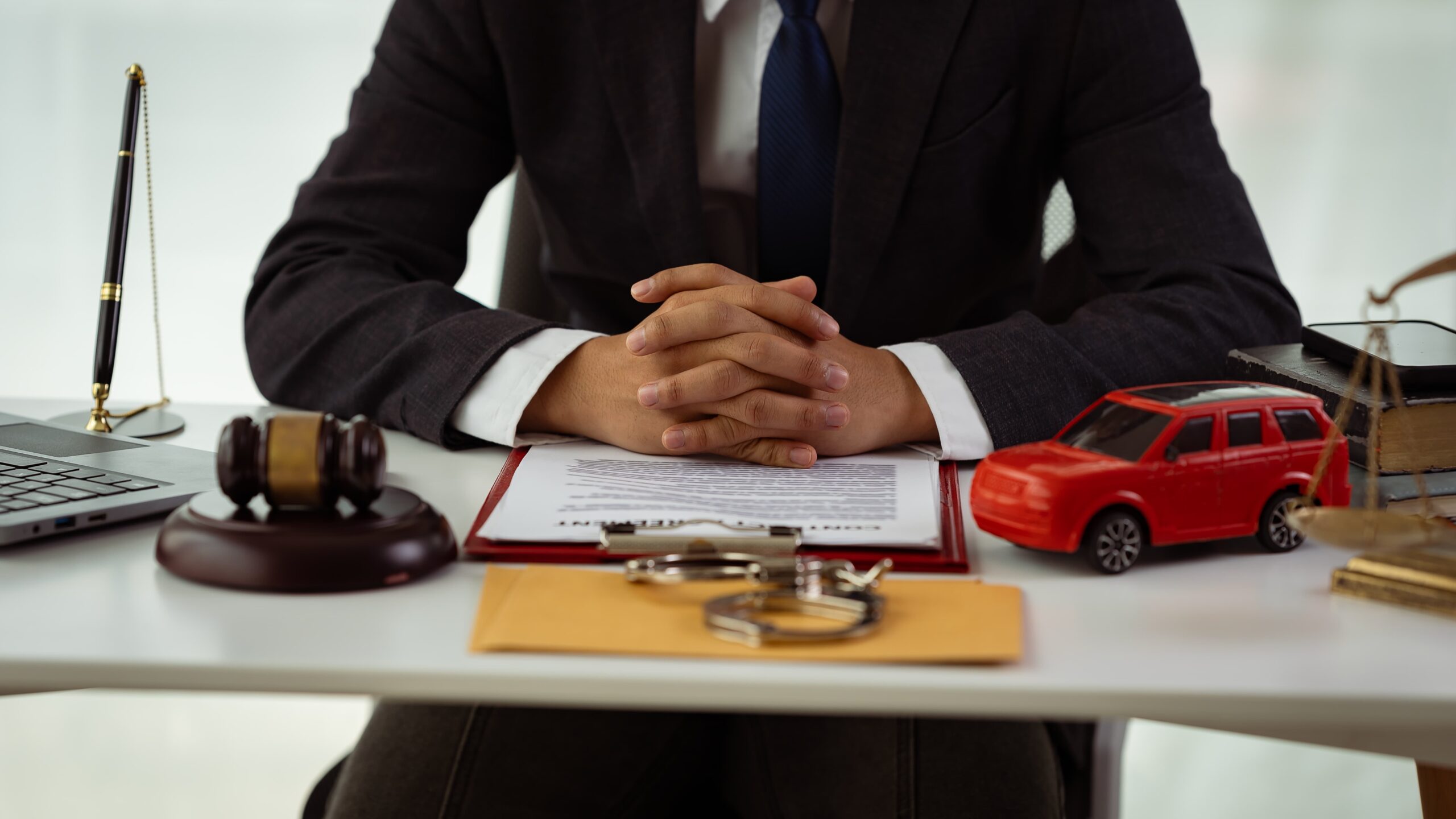 Car accident law 14 - The Ye Law Firm Injury Lawyers Crashed toy car models and a judge's gavel on a courthouse desk symbolize car law, insurance, auto tax, auctions, and bidding concepts.