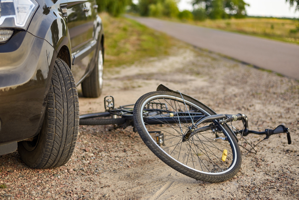 Bicycle lying beside a car after an accident on a rural road, representing a bicycle accident case in Bellevue