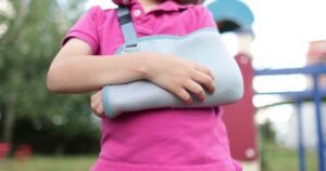Child with an arm cast standing in a playground, representing a dog bite injury