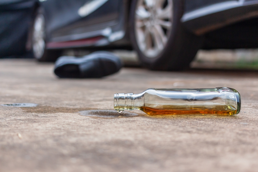 Empty liquor bottle near a car after a crash, symbolizing a drunk driving accident in Bellevue