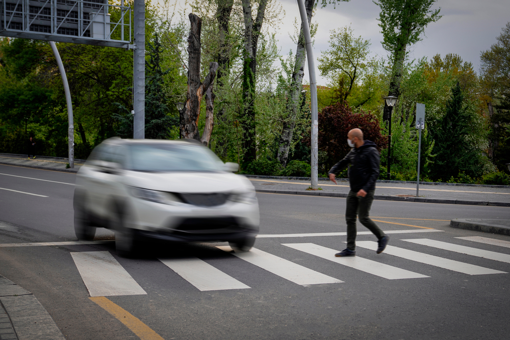 Car approaching a pedestrian in a crosswalk, illustrating a pedestrian accident scenario in Bellevue WA