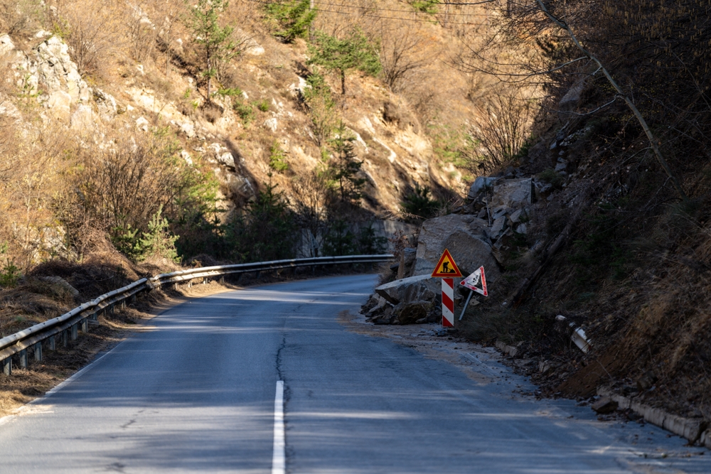 시골 도로를 막고 있는 큰 바위와 잔해는 자연적 위험이 어떻게 자동차 사고를 일으킬 수 있는지 보여줍니다.