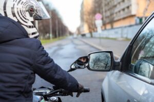 Road rage Motorcyclist stands by side with car on the road - Concept of a Road Rage Drivier