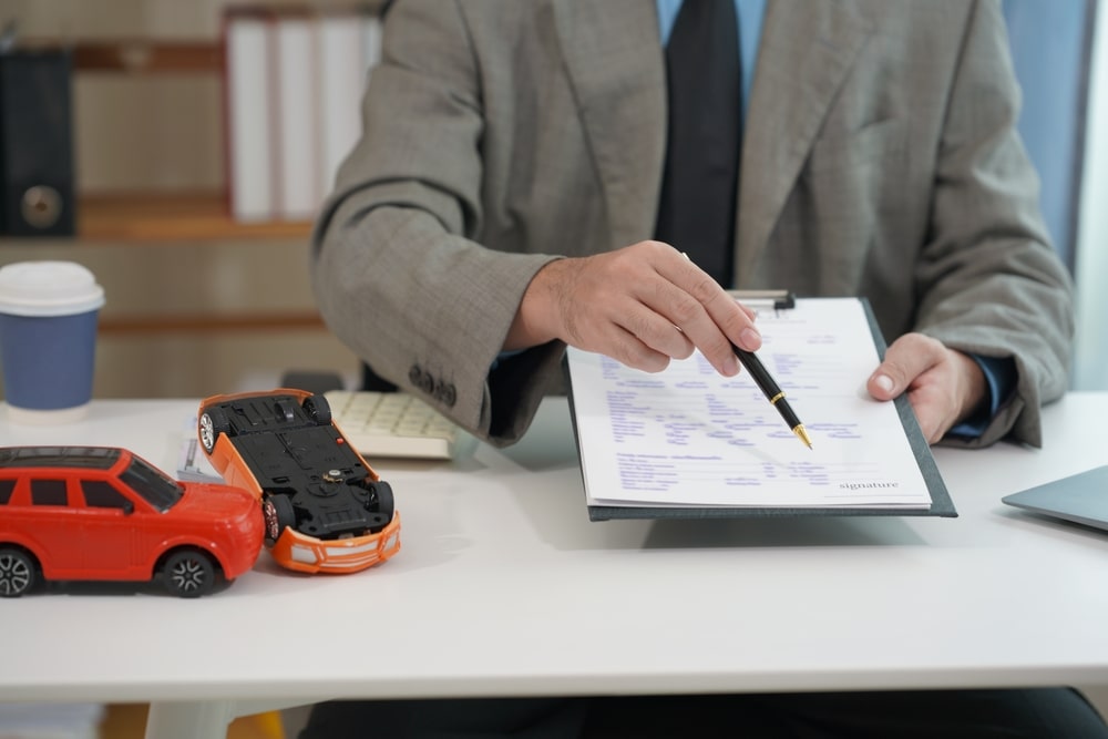 Attorney reviewing injury claim documents with car accident models on a desk
