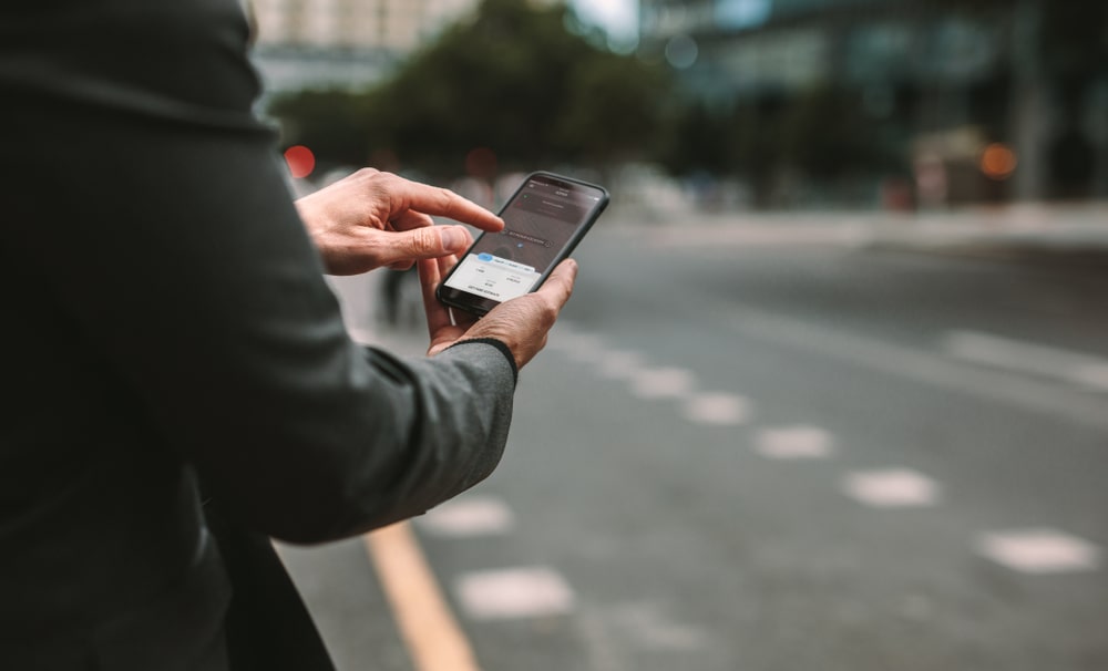 Person using a smartphone on a city street after a rideshare trip